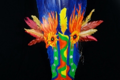 Head of State #3 golden eyes surrounded with gold and orange feathers on face painted on queen palm