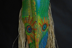 Head of State #13 dots and patterns highlight large round eyes in greens, orange, yellow and blues on queen palm frond